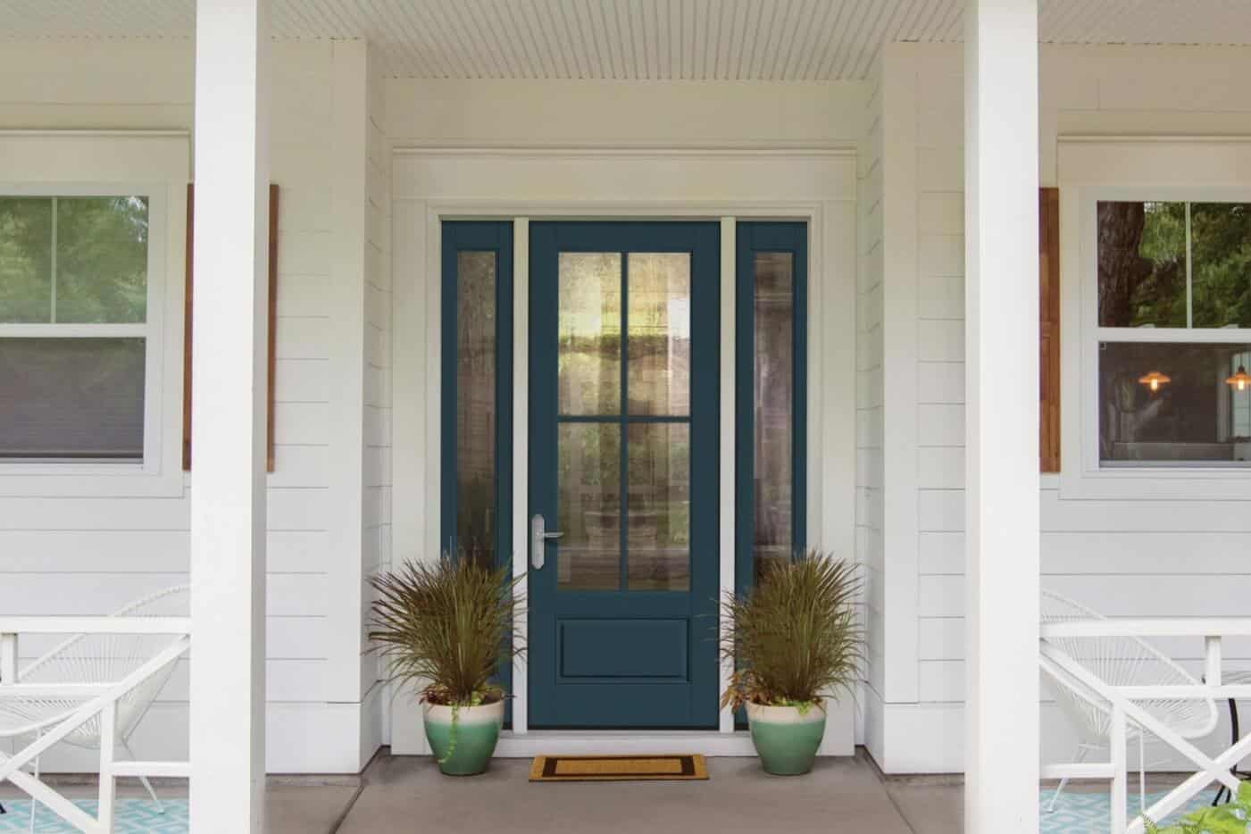 Front porch with a dark blue door flanked by windows. Two potted plants sit on either side of the entrance, matching the crisp interior doors visible through the glass. White chairs add charm on both sides of the porch.